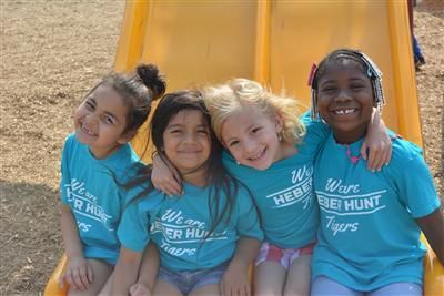 A group of young girls are sitting on a slide together.