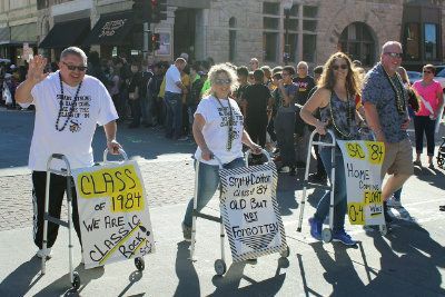 A group of people are walking down a street holding signs that say class of 1981.