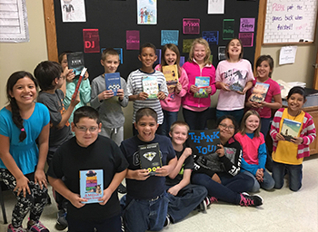 A group of children holding books and a sign that says thank you