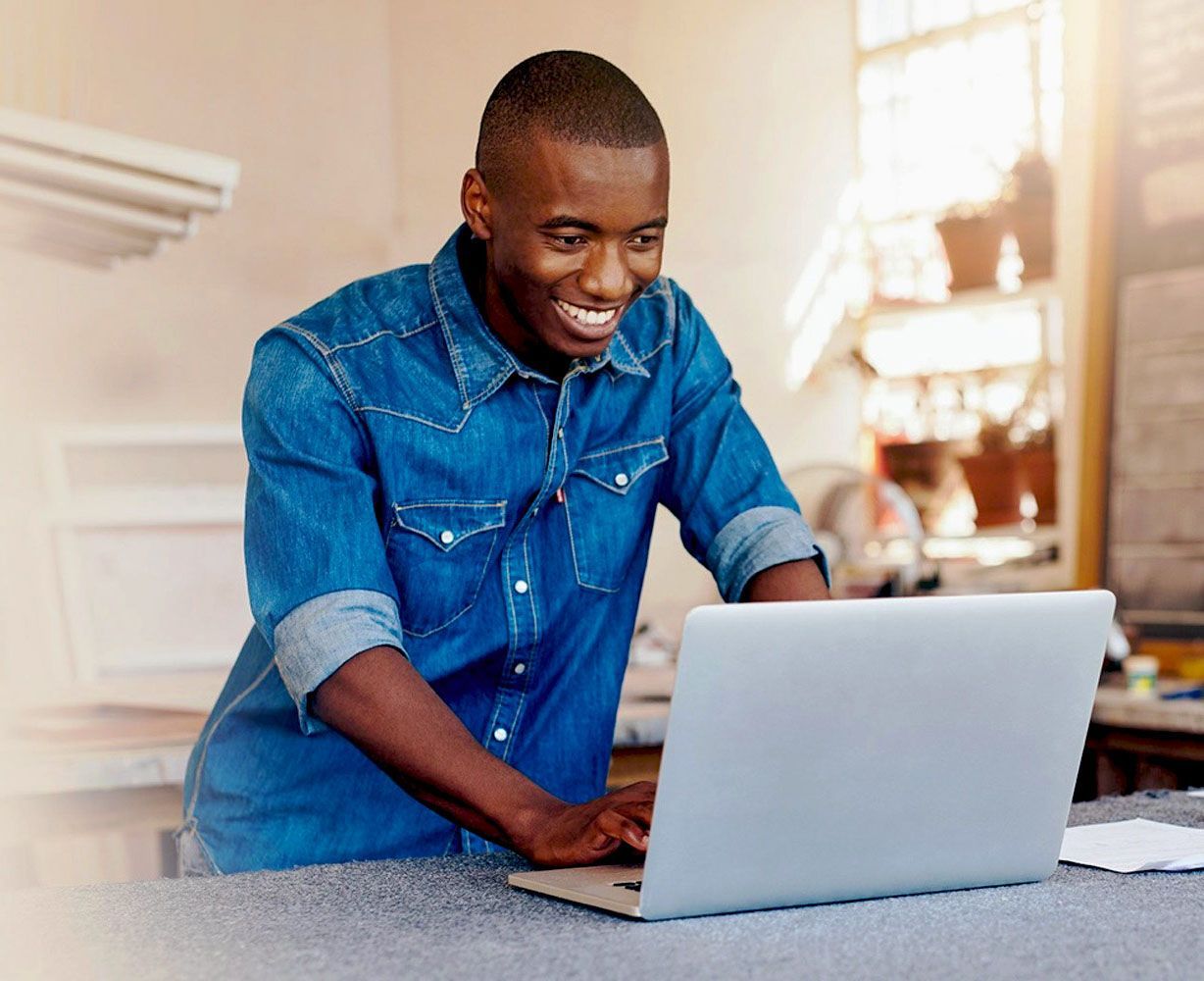 Un homme en chemise en jean utilise un ordinateur portable.