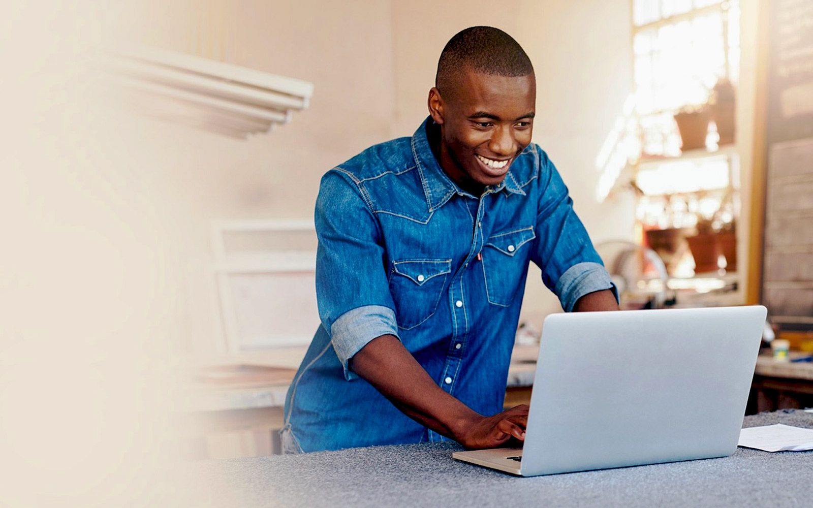 Un homme est assis à une table en train d'utiliser un ordinateur portable.