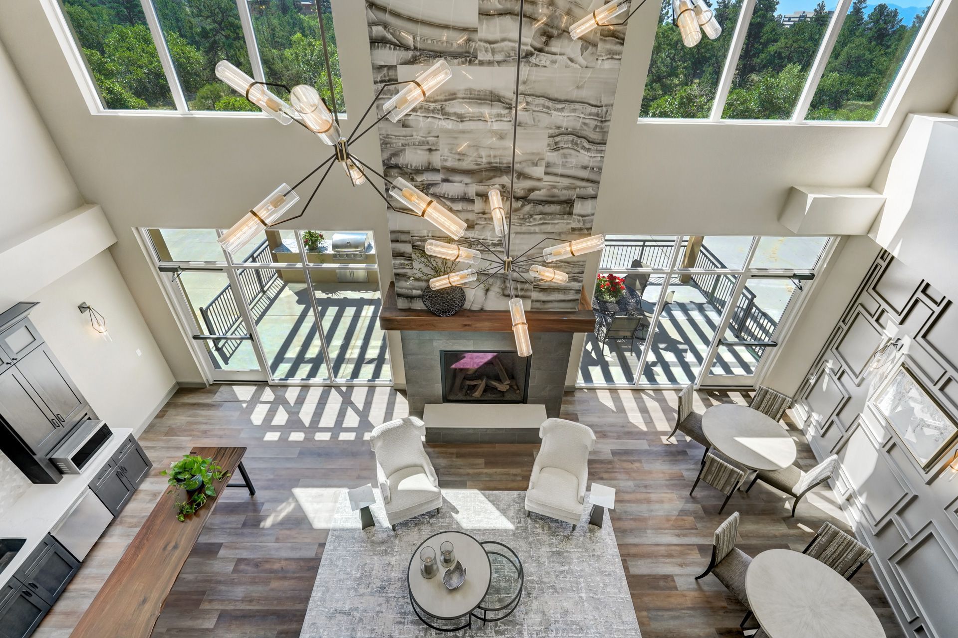 High-angle view of a modern living room with a fireplace, large windows, and a chandelier.