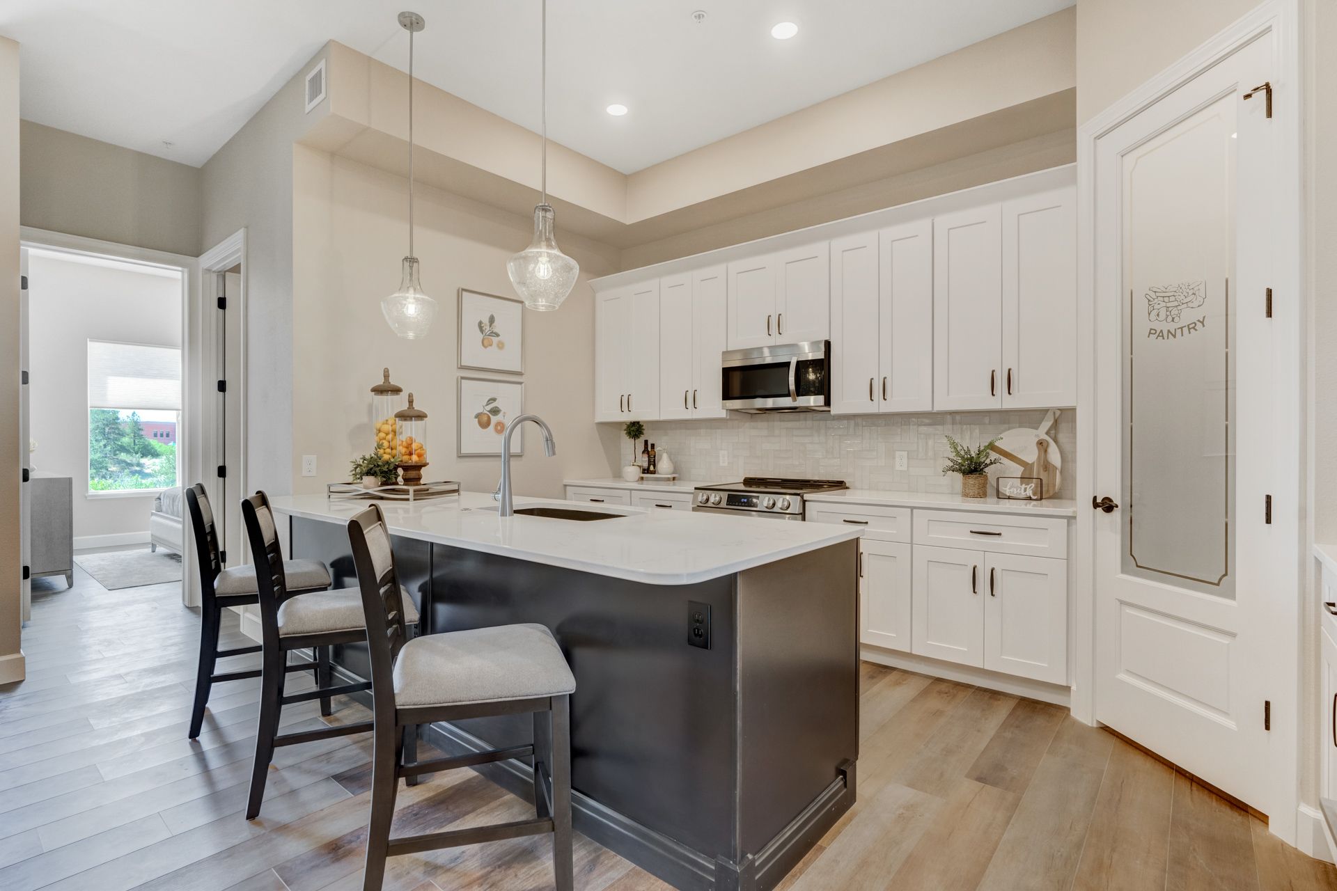 Modern kitchen with white cabinets, gray island, and wooden floors.