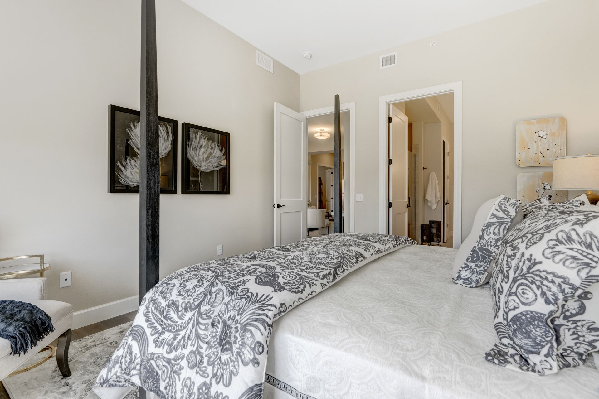 Bedroom with a bed covered in a patterned comforter, a chair, and doors leading to other rooms.