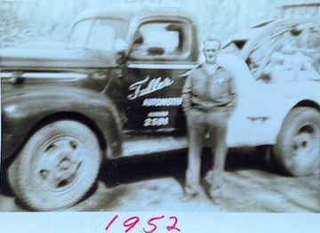 A man standing next to a truck that says taller automotive