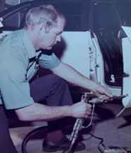 A man in a blue shirt is working on a car