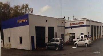 A picture of a car dealership with cars parked in front of it