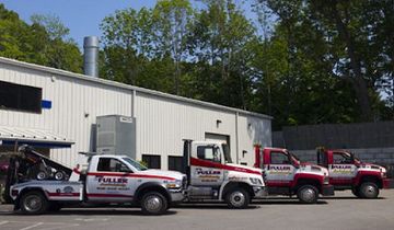 Three tow trucks are parked in front of a building.