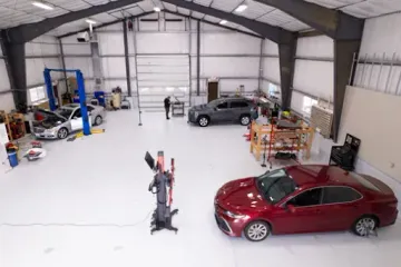 A red car is parked inside of a large garage.