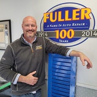 A man is standing in front of a fuller auto repair sign.