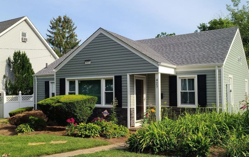 A small house with a gray roof and black shutters