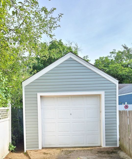 A garage with a white door is surrounded by trees
