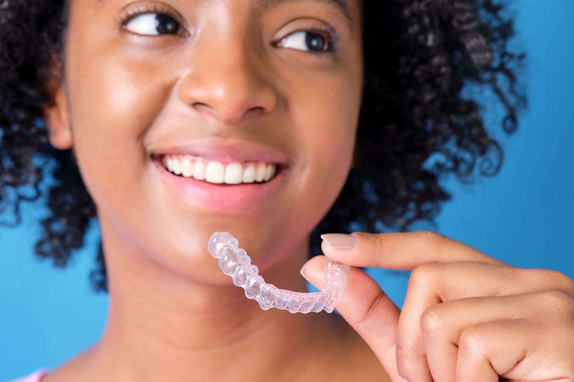 A young girl is holding a clear brace in her hand.