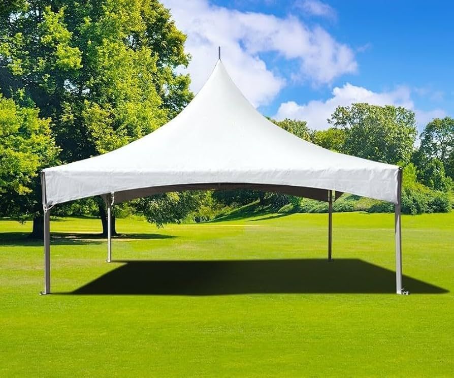 A white high-peak frame tent stands on a lush green grass lawn against a backdrop of trees and a blue, cloudy sky.
