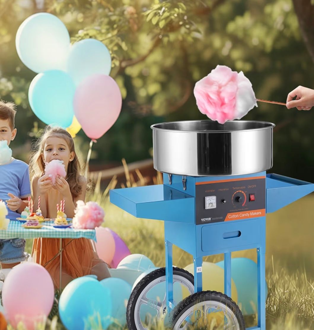 A blue cotton candy machine stands in a grassy field with colorful balloons and children nearby.