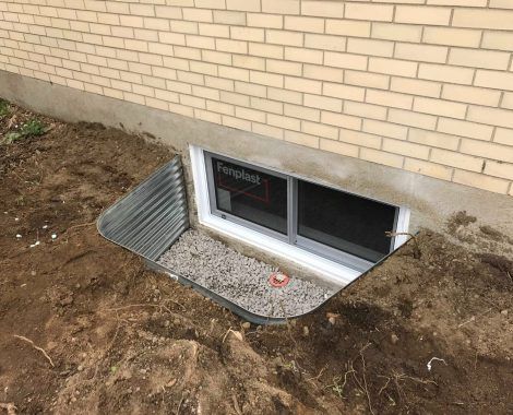 Une fenêtre dans le sol à côté d'un mur de briques.