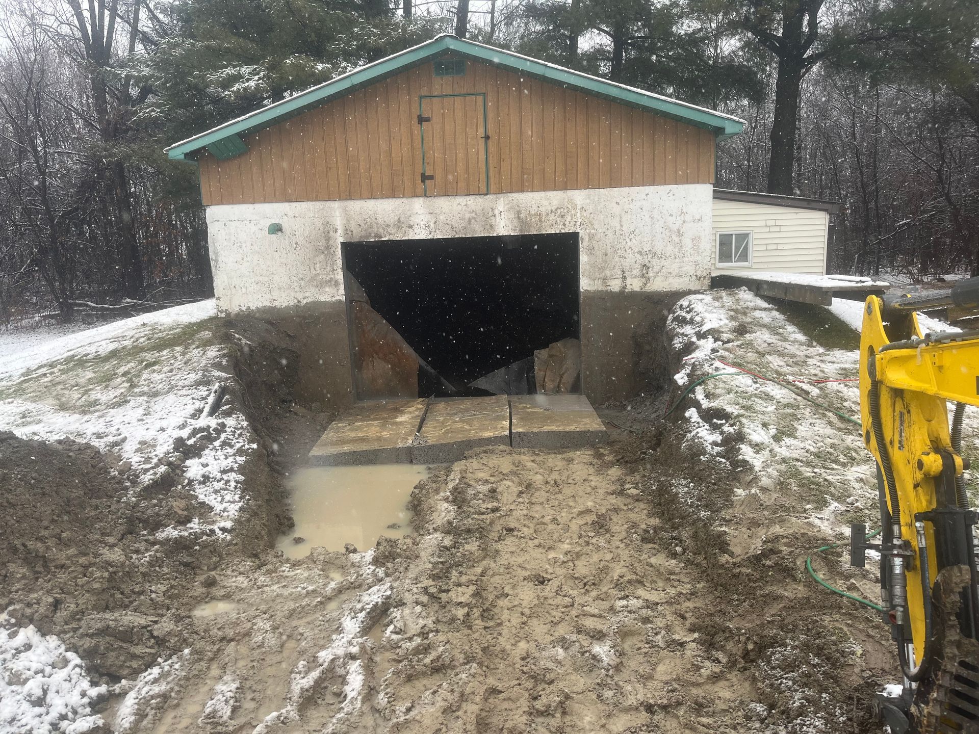 Une excavatrice jaune creuse un trou devant un bâtiment.