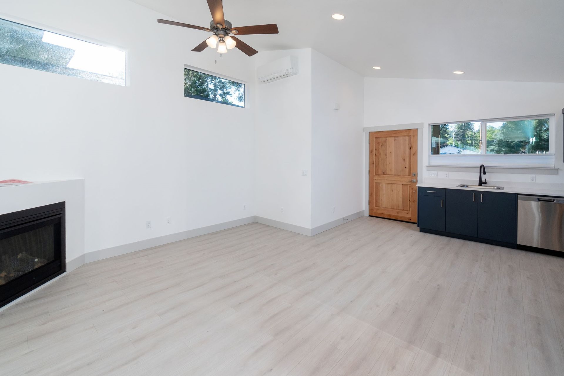 An empty living room with a fireplace and ceiling fan.