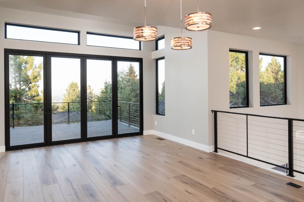 An empty living room with hardwood floors , sliding glass doors , and a balcony.