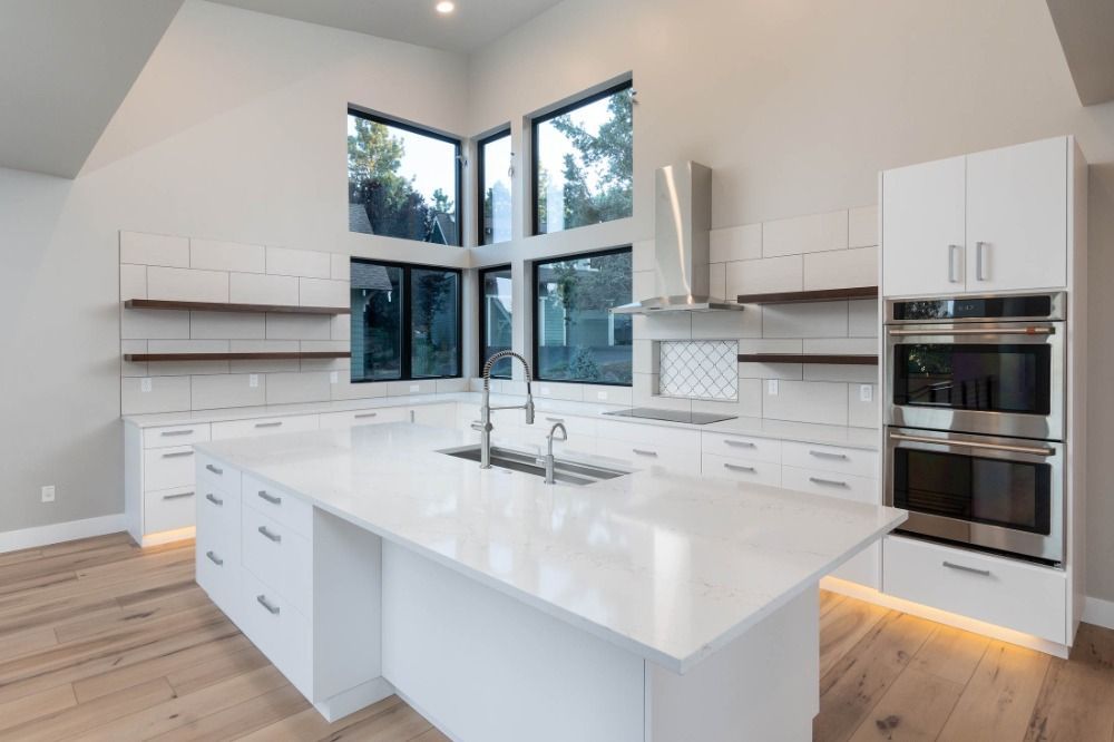 A kitchen with white cabinets and stainless steel appliances and a large island.