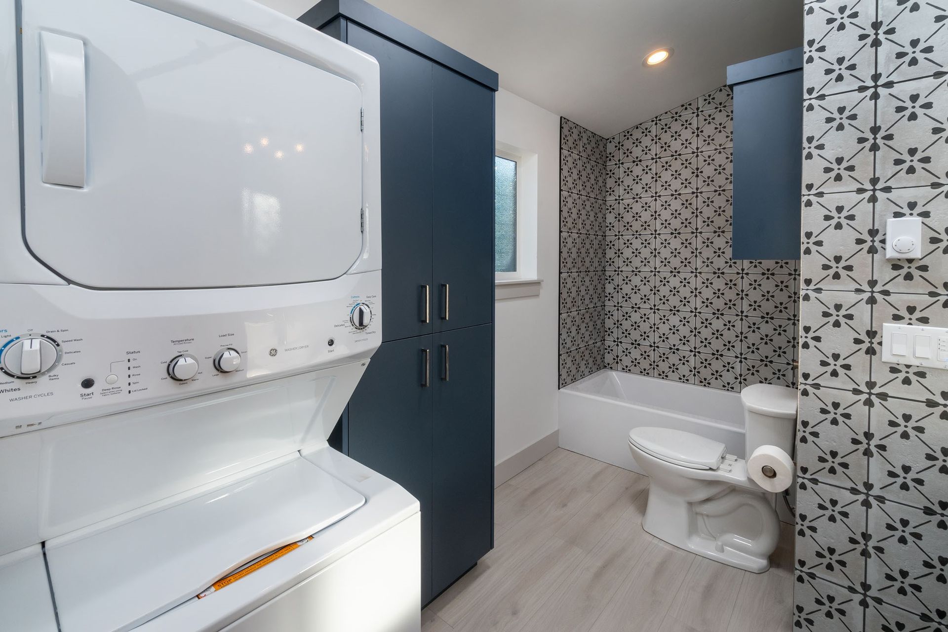 A bathroom with a washer and dryer stacked on top of each other.