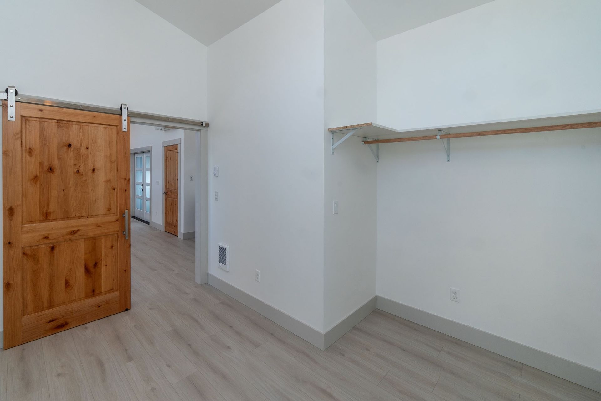 An empty closet with sliding barn doors and shelves.