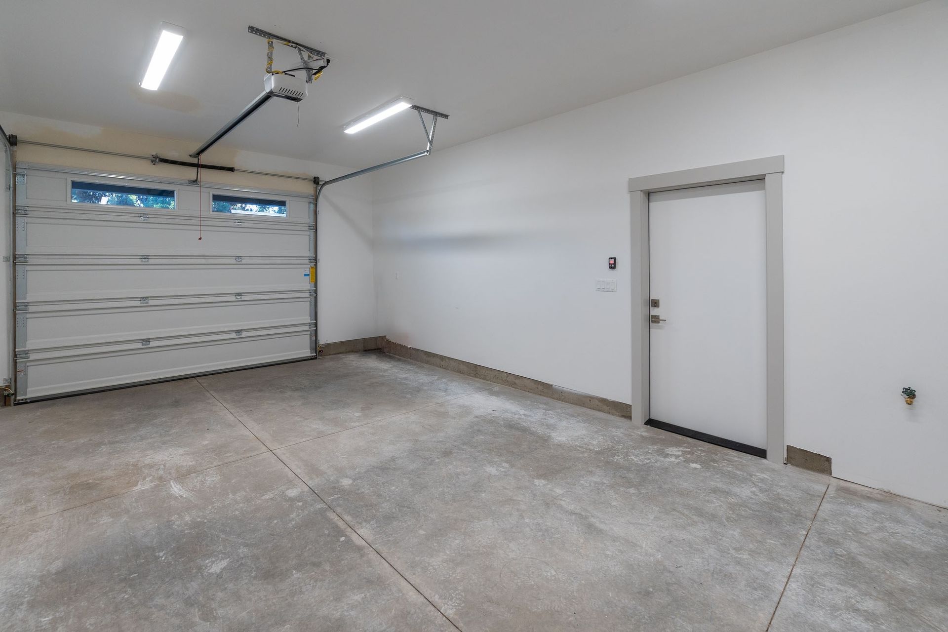 An empty garage with a garage door open and a door.
