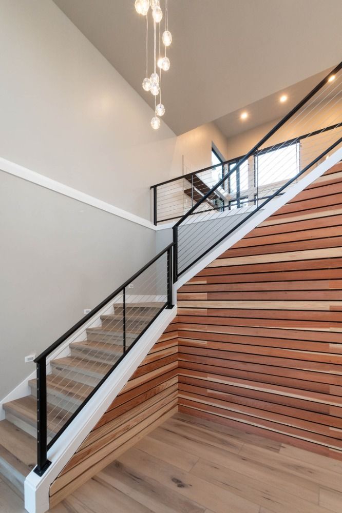 A staircase with a wooden wall behind it and a glass railing.