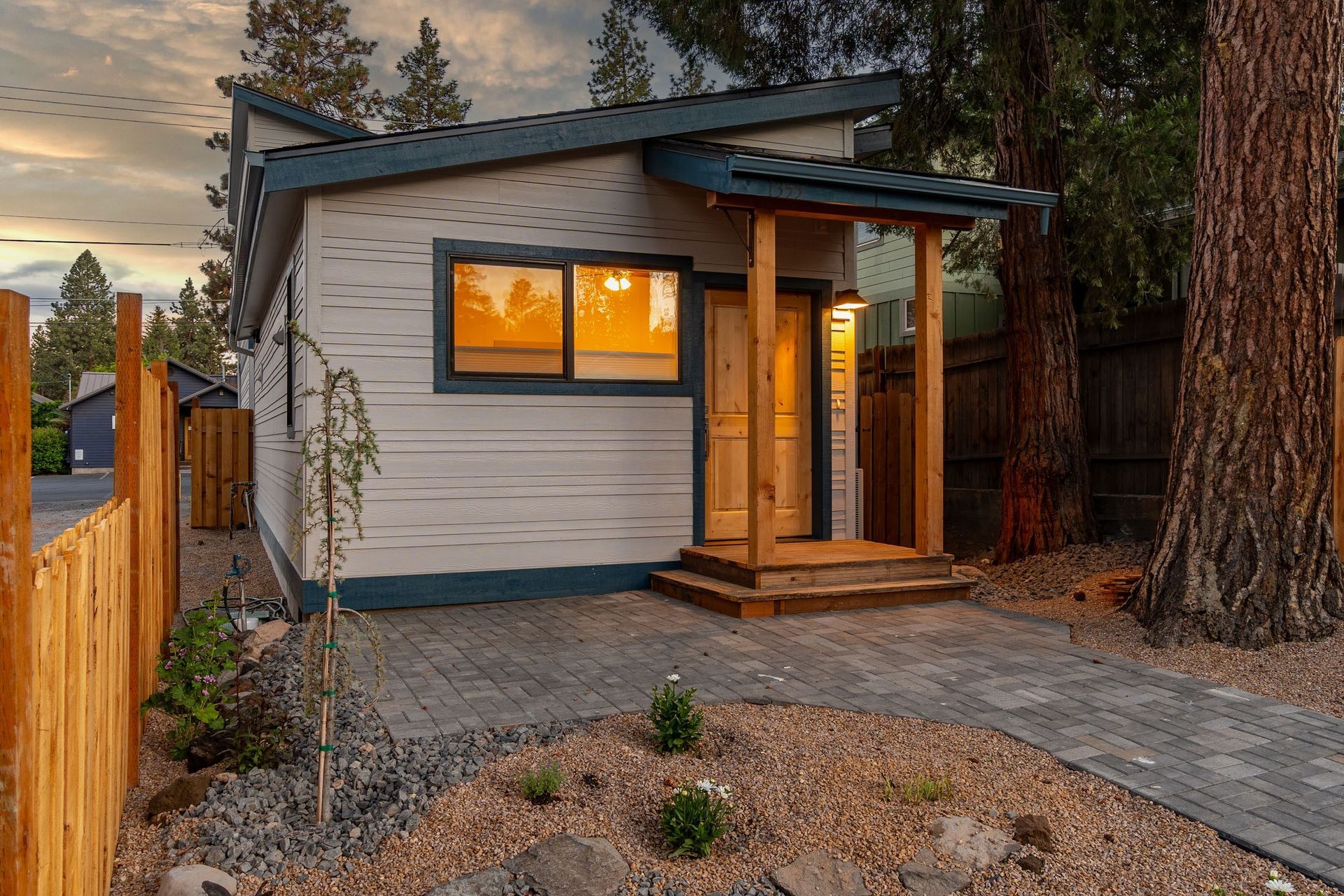 A small house with a porch and a wooden fence in front of it.