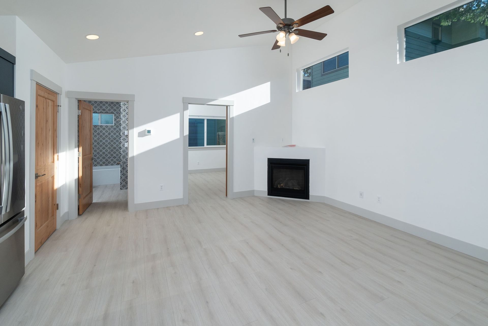 An empty living room with a fireplace and ceiling fan