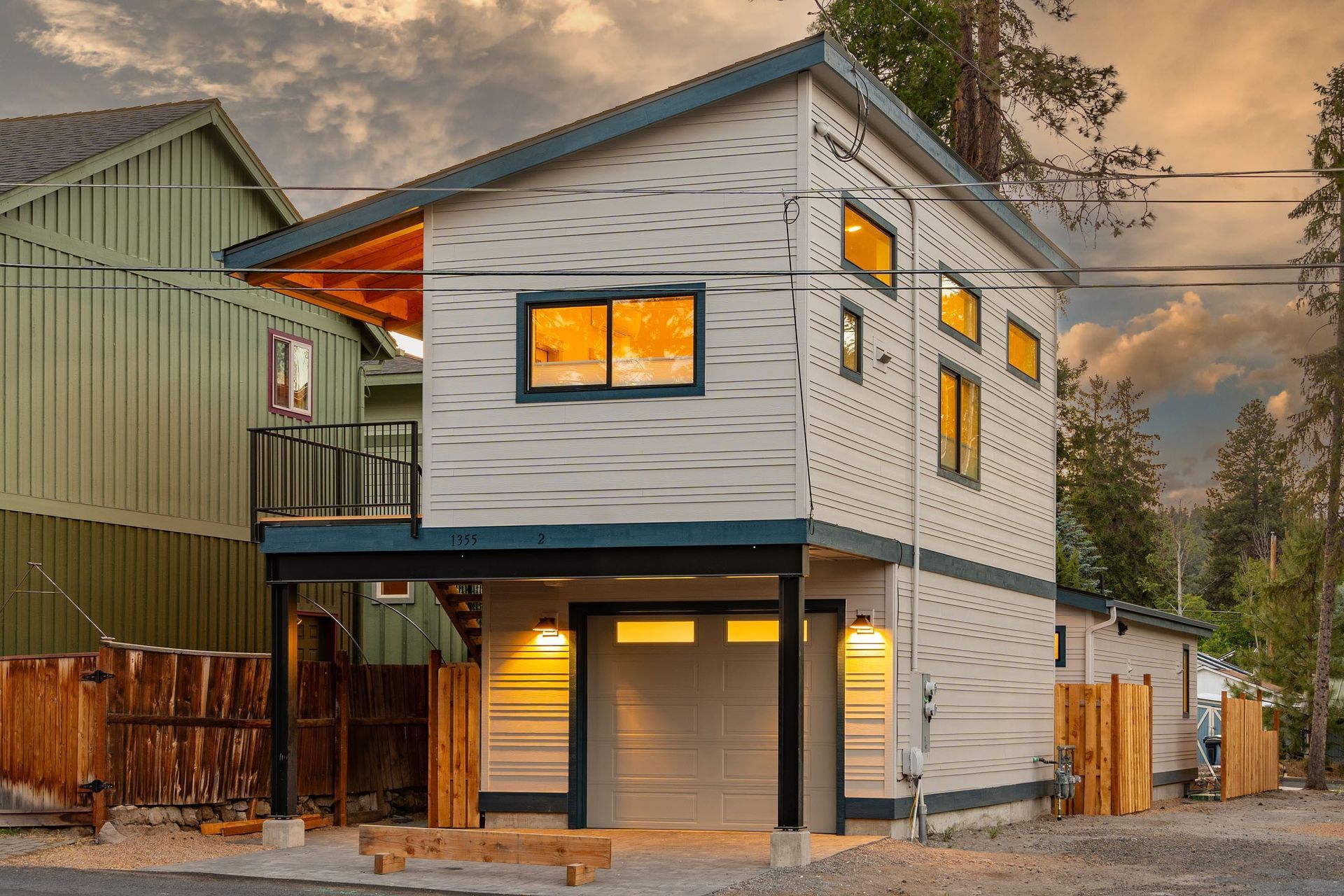 A small house with a garage and a balcony is sitting next to a green house.