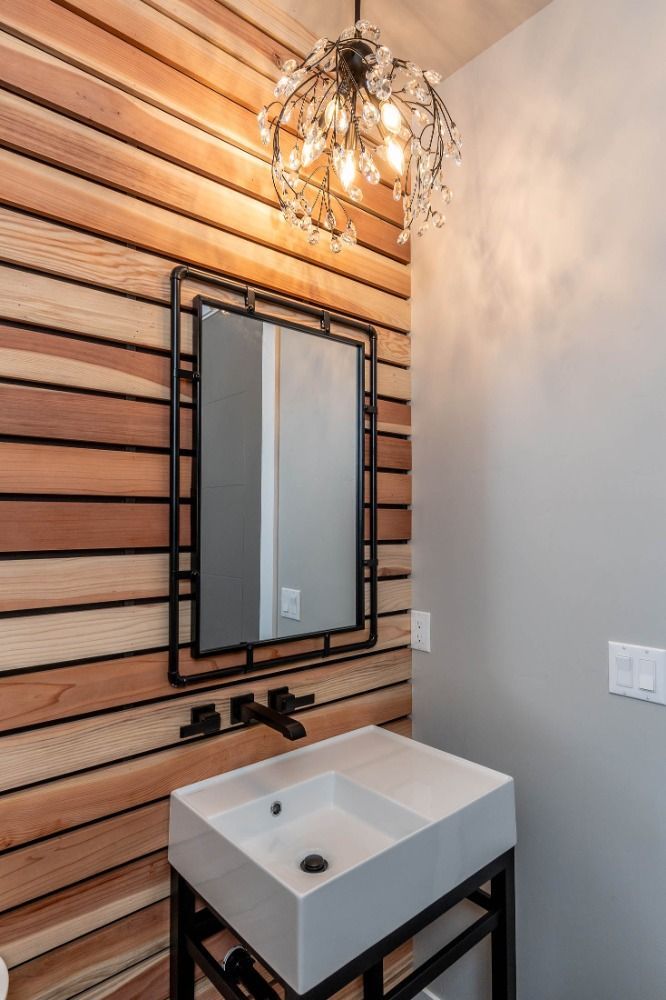 A bathroom with a sink , mirror and chandelier.