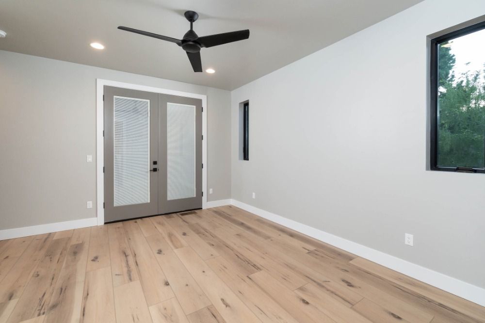 An empty room with hardwood floors and a ceiling fan.