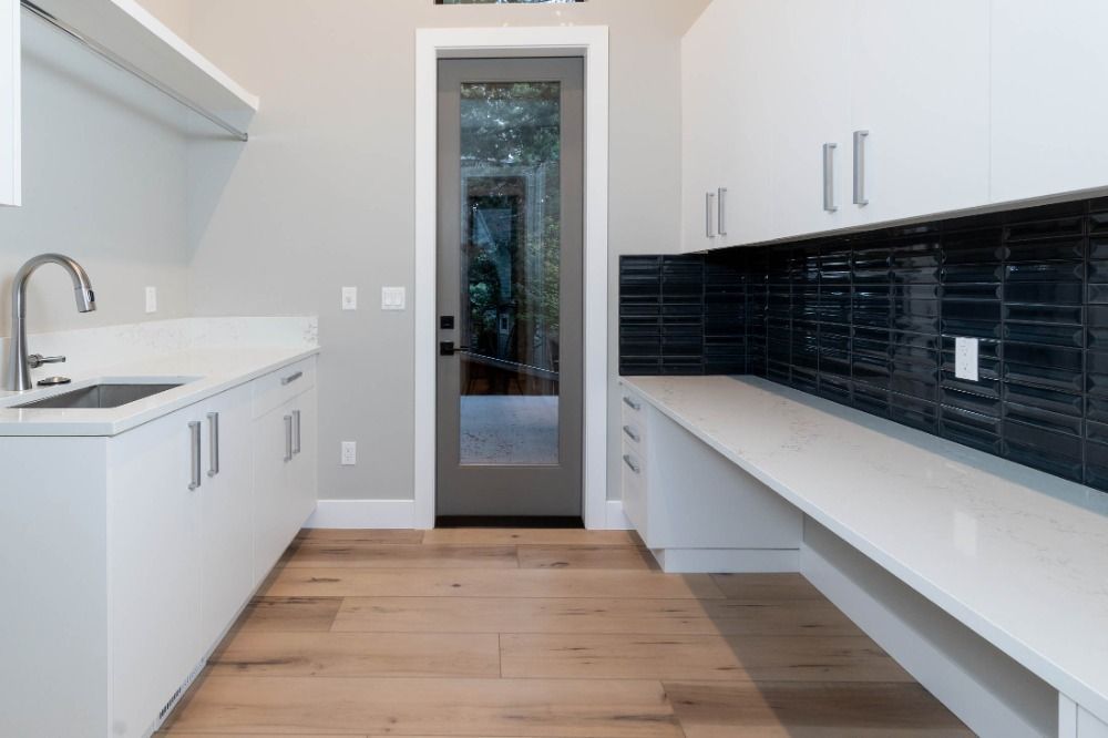 A kitchen with white cabinets , a sink , and a door.