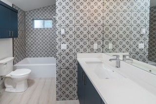 A bathroom with a toilet , sink , tub and mirror.