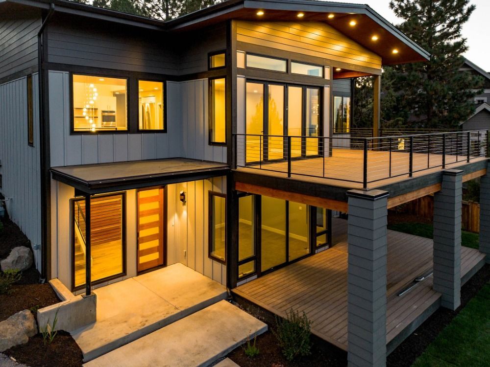 A modern house with a large deck and lots of windows.