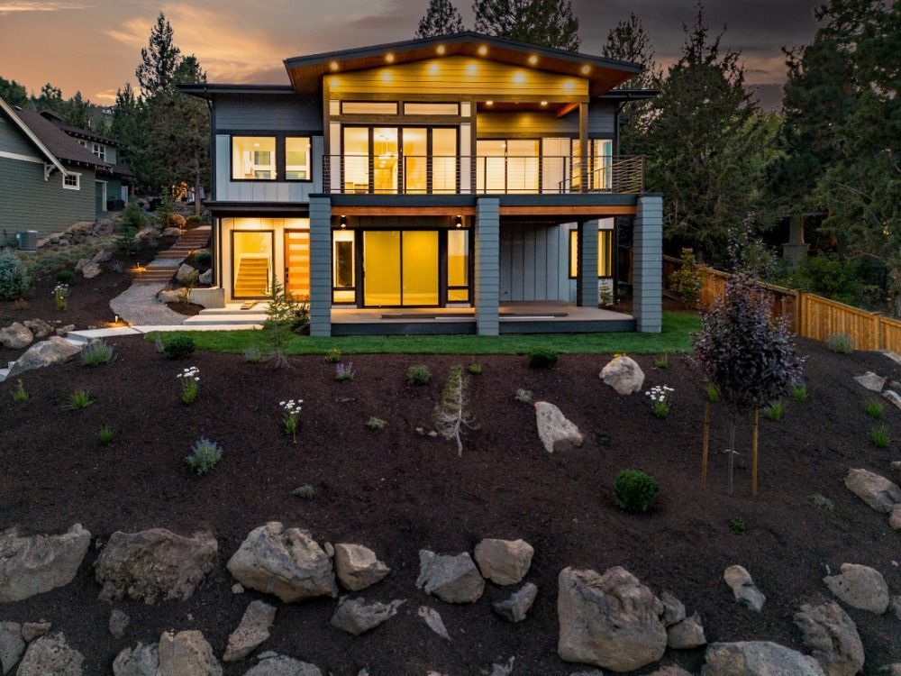 A large house is sitting on top of a hill surrounded by rocks.