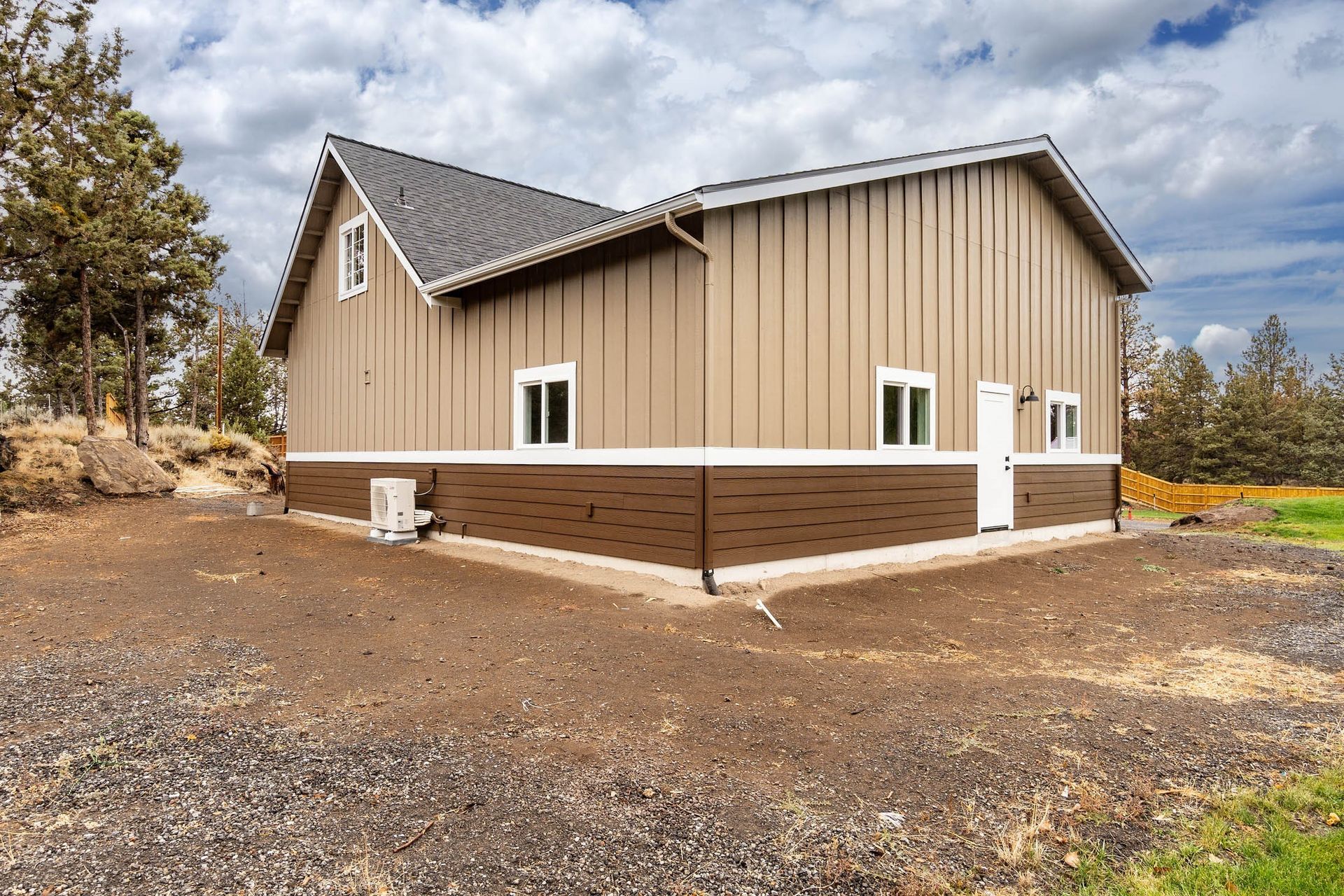 A large house with a lot of windows is sitting on top of a dirt field.