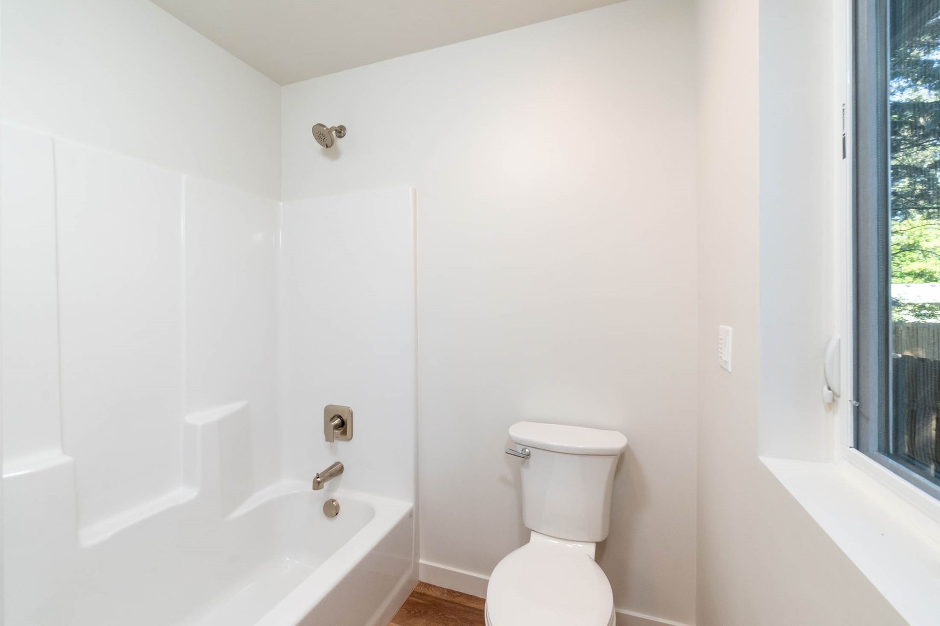 A bathroom with a toilet , bathtub and shower.