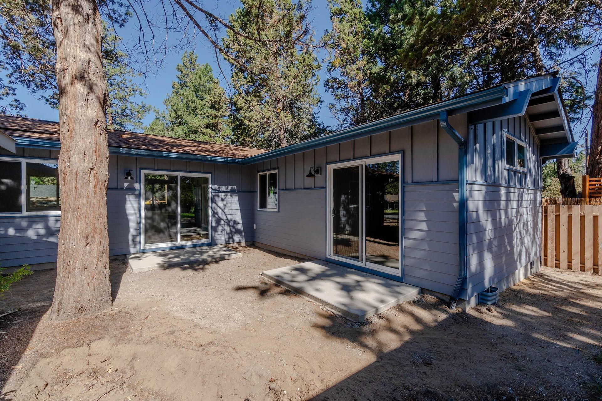 The backyard of a house with sliding glass doors and a tree.