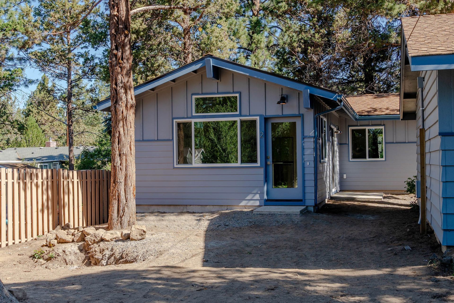 A small house with a fence and trees in the background