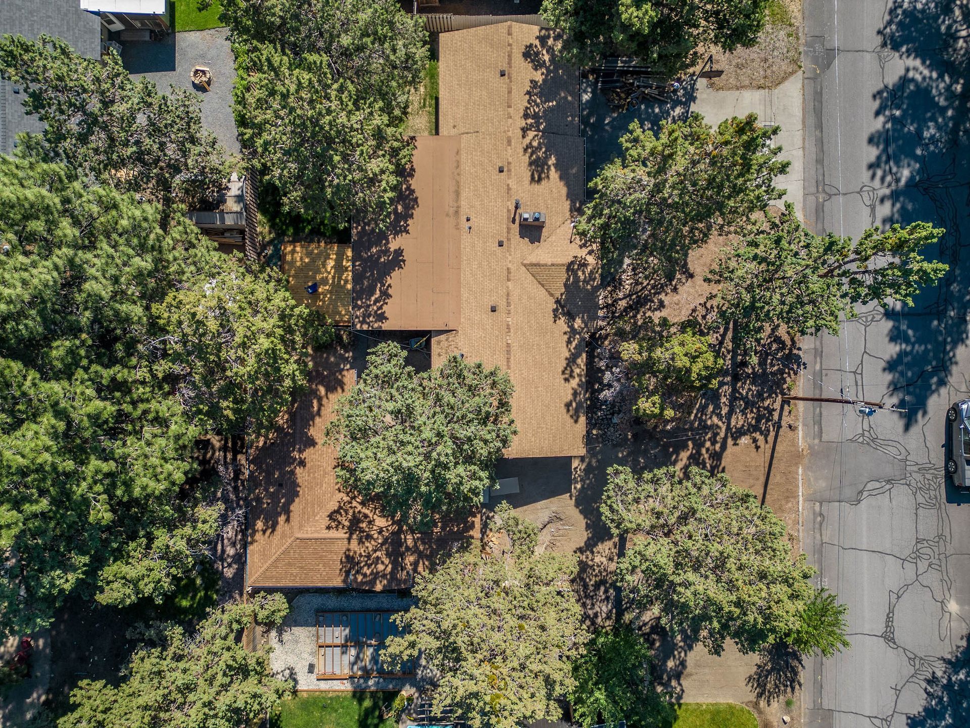 An aerial view of a house surrounded by trees and a road.