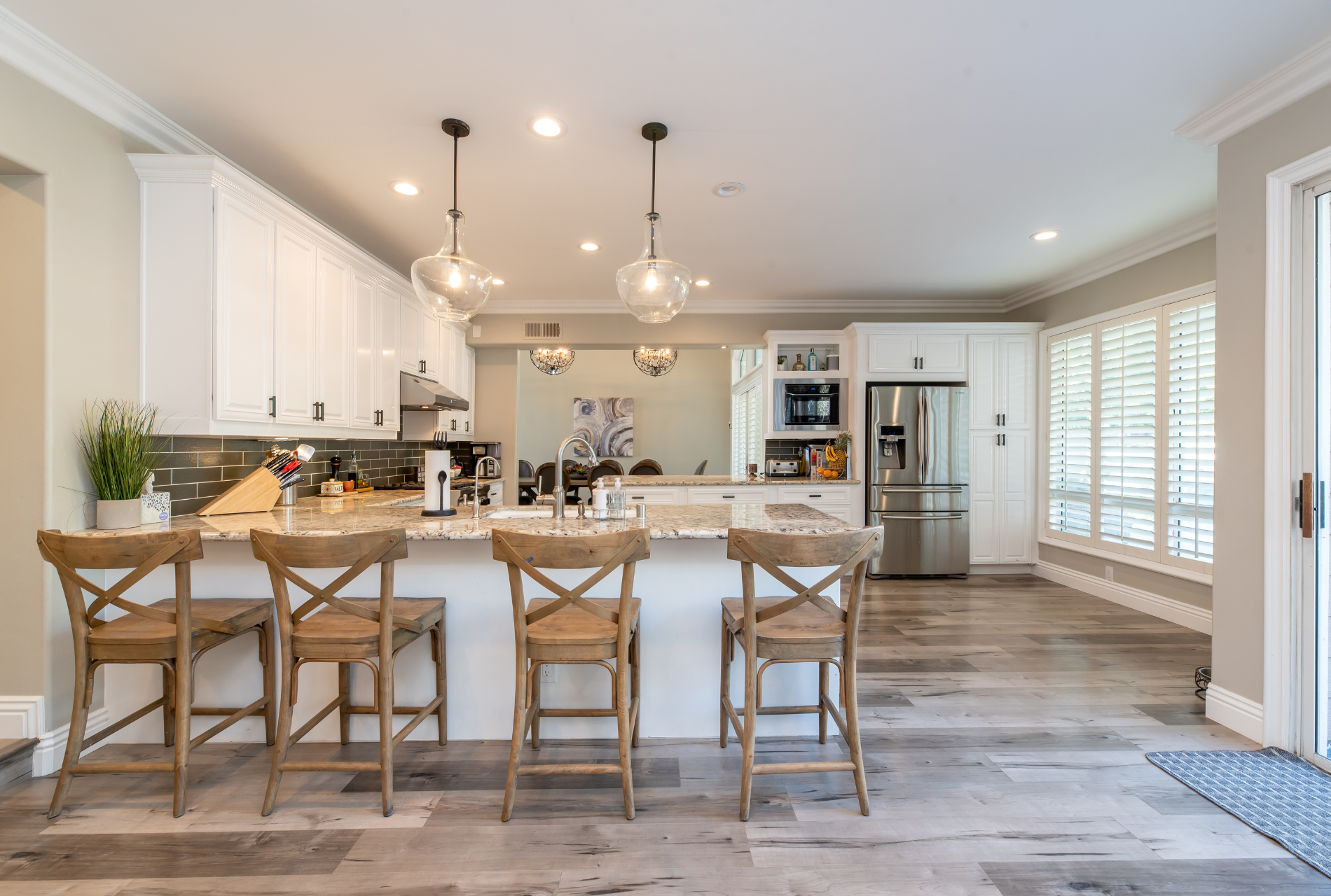 A kitchen with white cabinets , stainless steel appliances , and wooden floors.