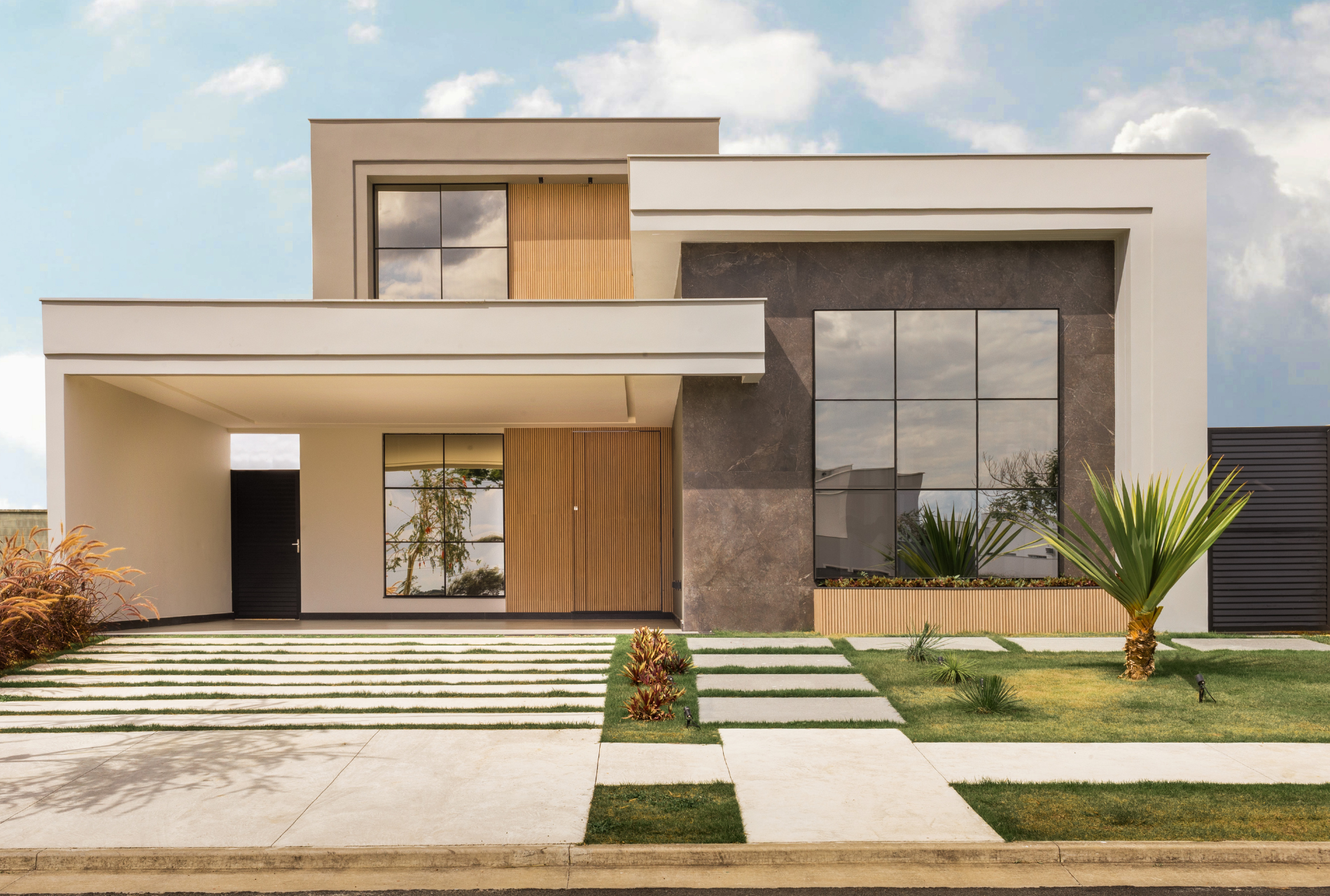 A modern house with a lot of windows and a concrete driveway