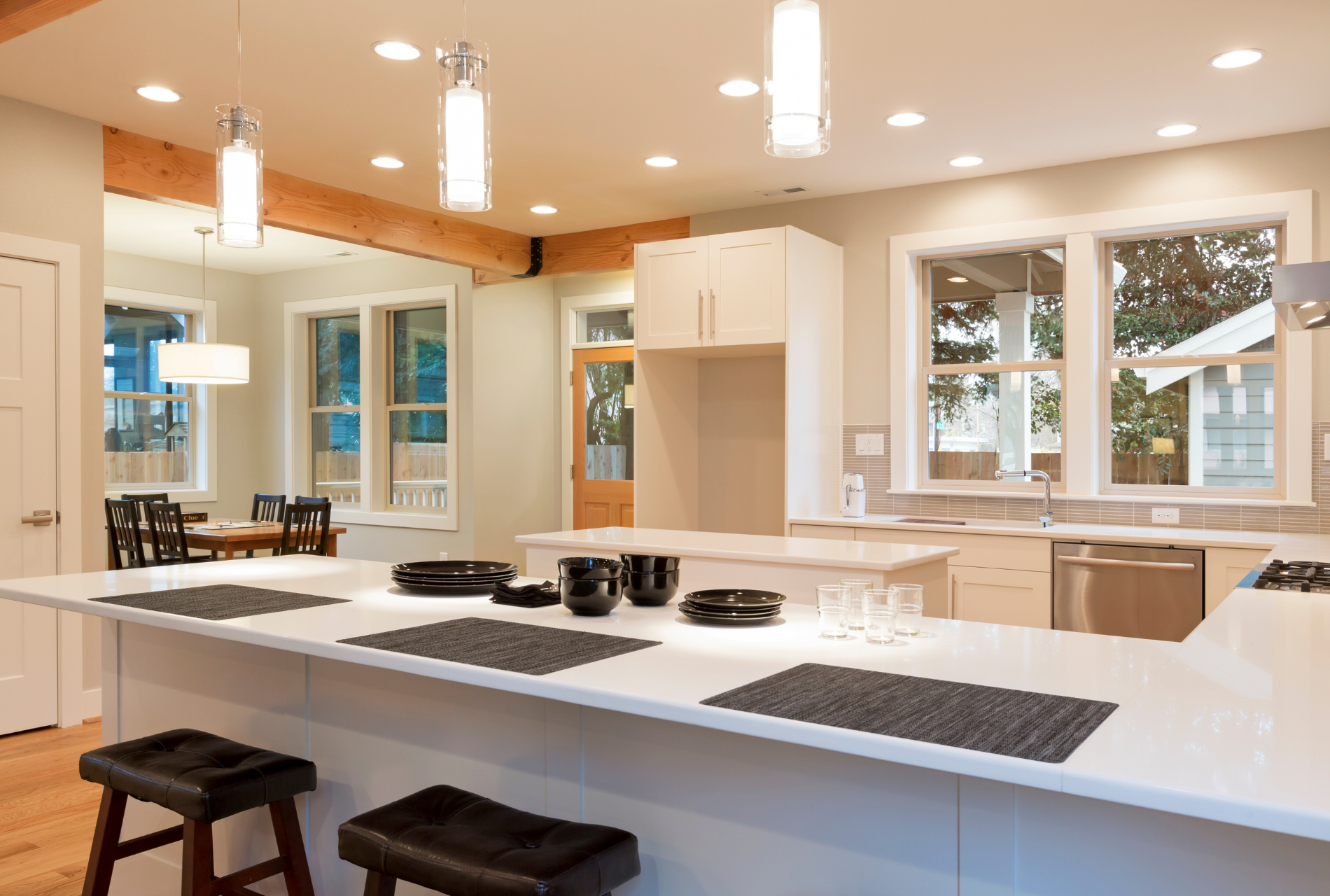 A kitchen with white cabinets , white counter tops , stainless steel appliances , and a large island.