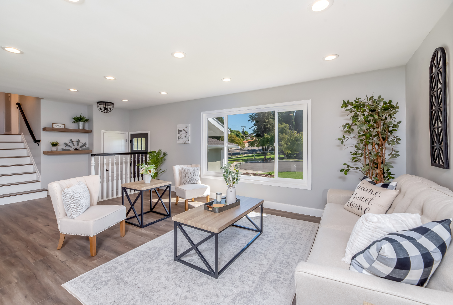 A living room with a couch , chairs , coffee table and stairs.