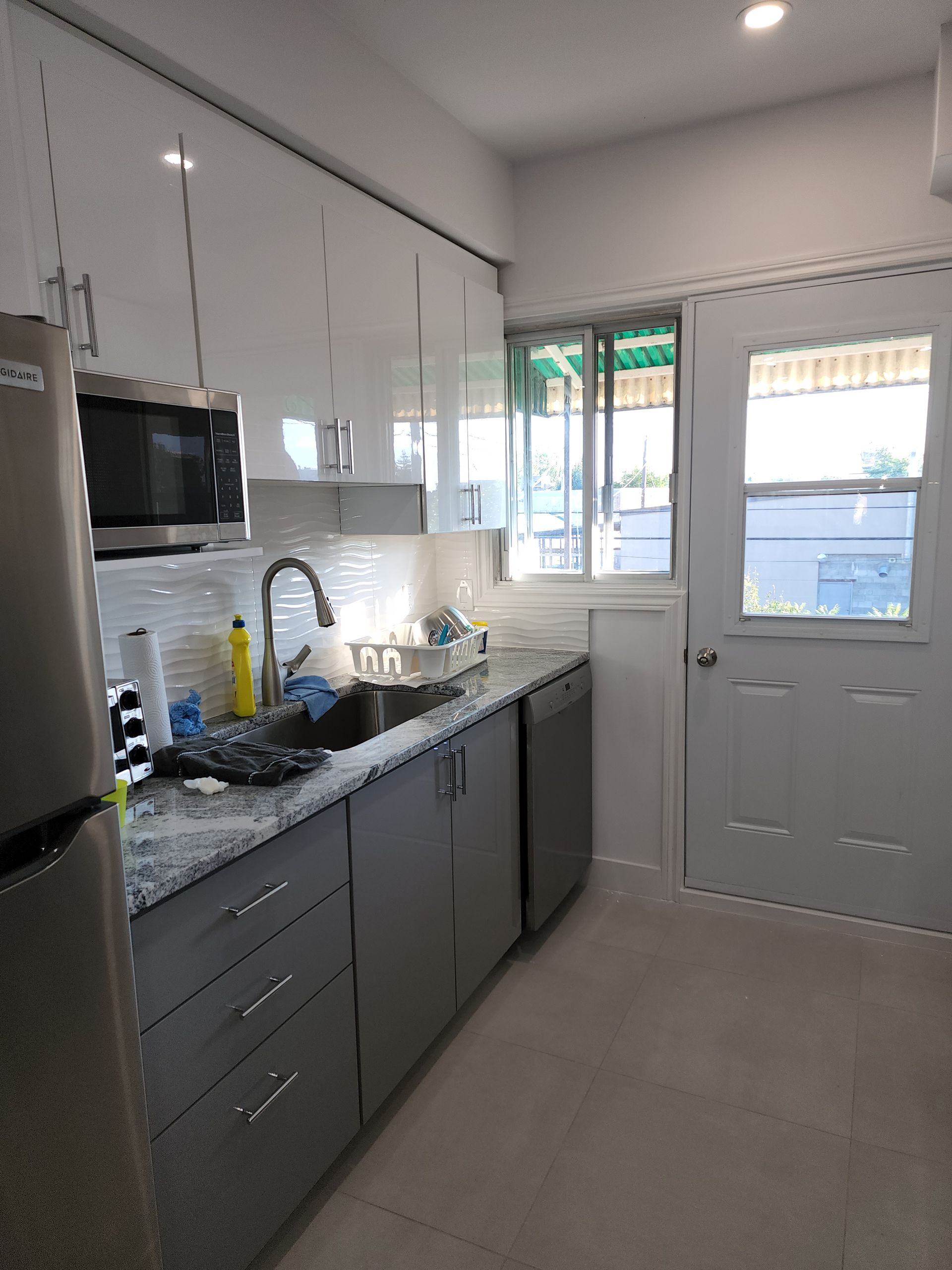 Une cuisine avec évier, réfrigérateur, micro-ondes et lave-vaisselle.