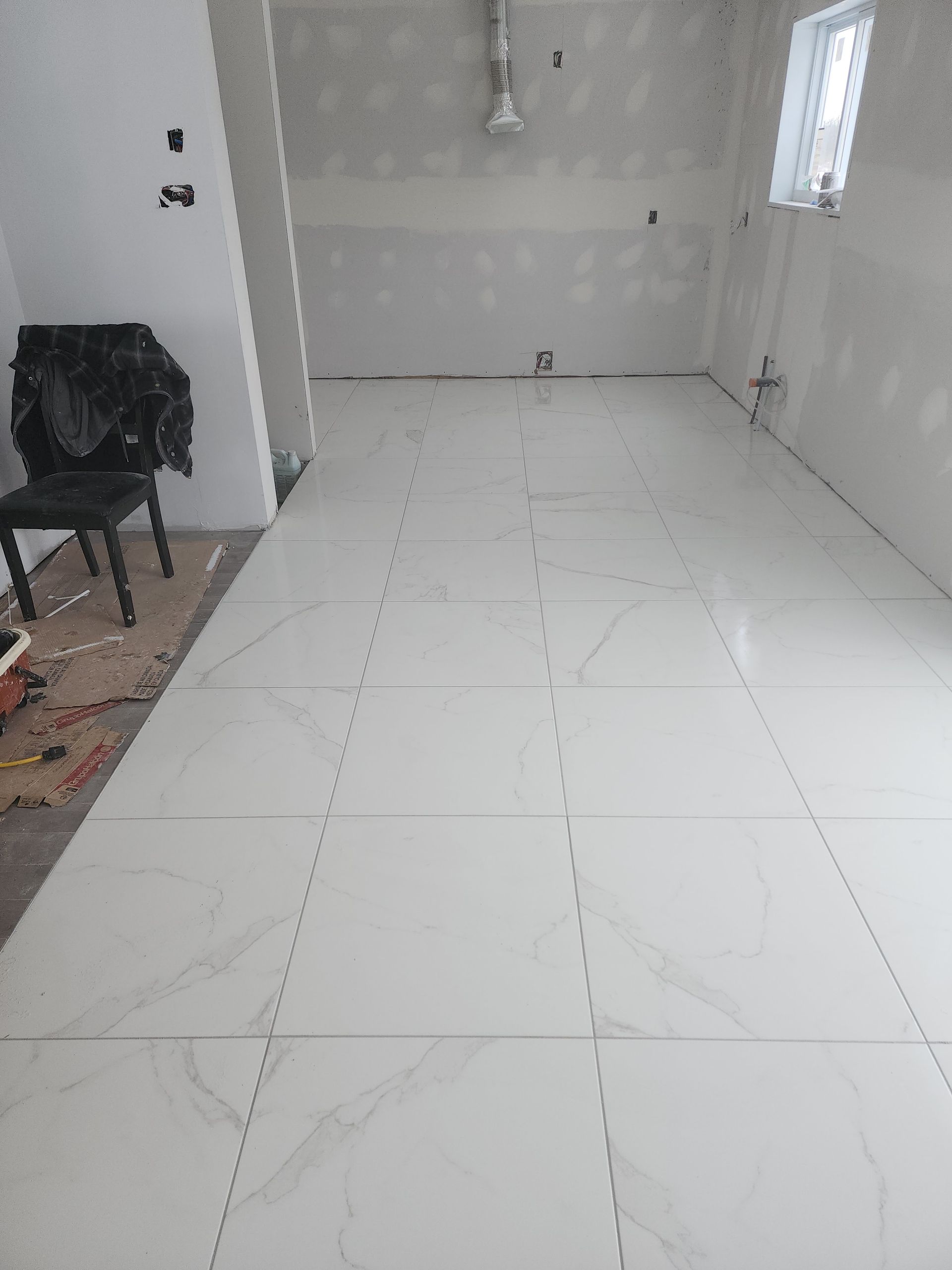 Une pièce avec du carrelage blanc au sol et une chaise dans le coin.