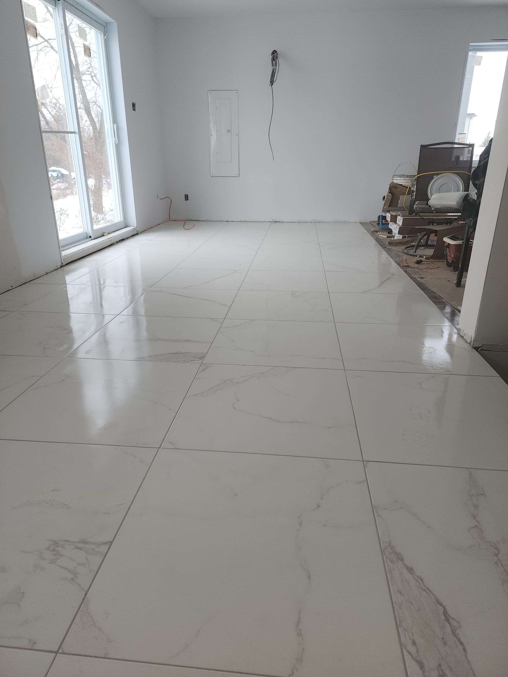 Un grand carrelage blanc au sol dans une pièce avec cheminée.