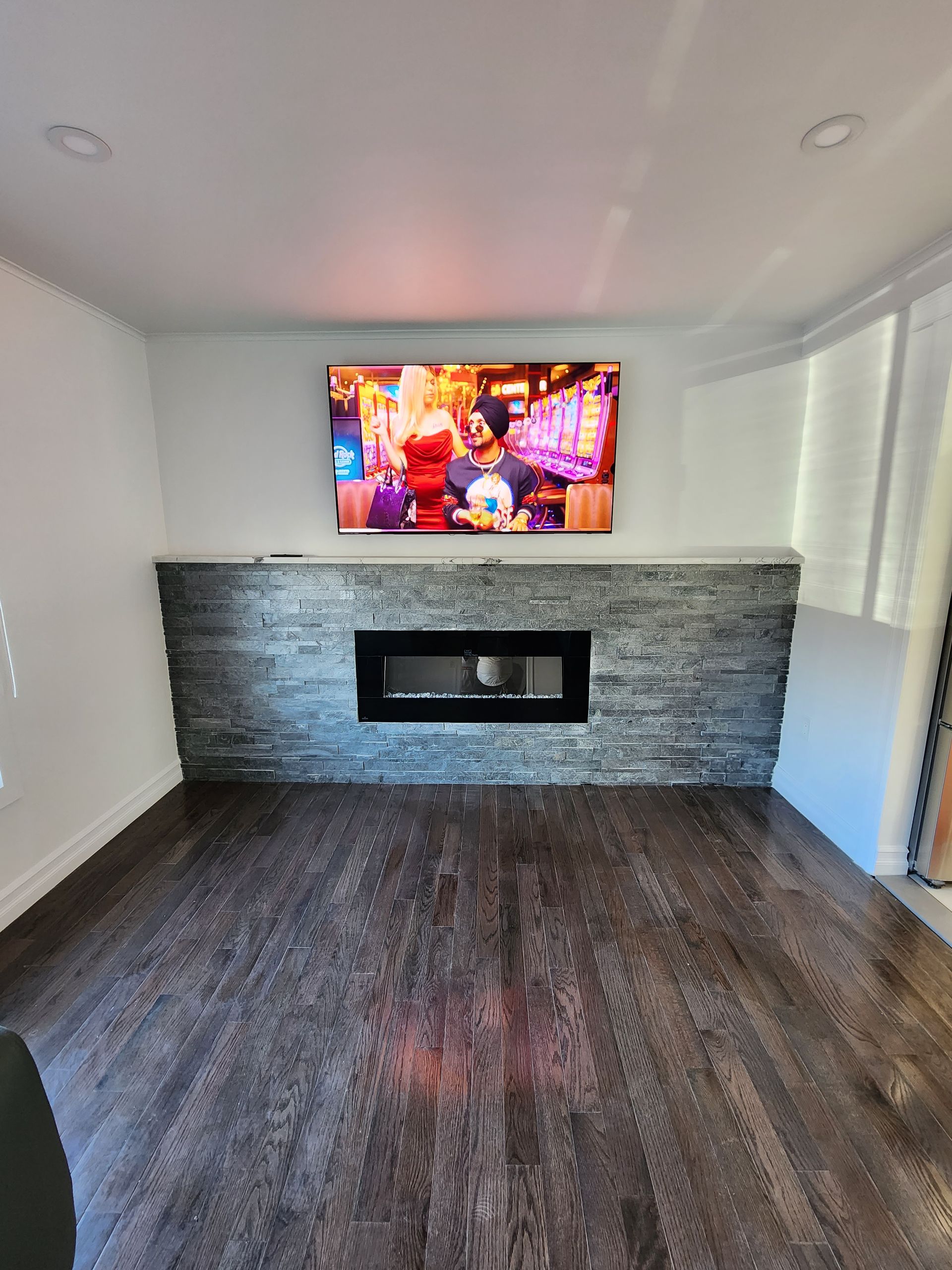 Un salon avec une cheminée et une télévision écran plat au mur.